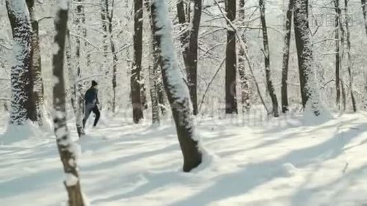 带着智能手表或心脏追踪器的年轻人在森林覆盖的冬季道路上奔跑视频