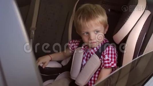 一个快乐的小男孩坐在棕色的儿童汽车座椅上，竖起大拇指。视频