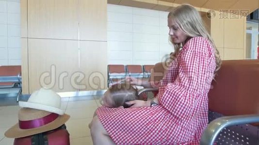 可爱的小女孩躺在她母亲的膝盖`机场的候车室里视频