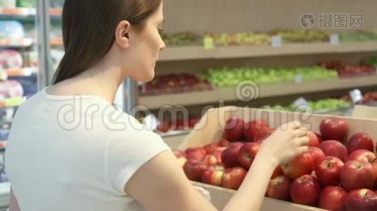年轻女子在杂货店买健康食品。 素食女孩选择新鲜的红苹果视频