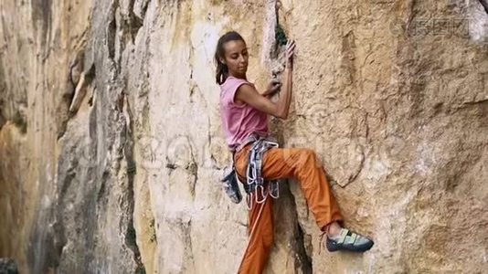 年轻的女性攀岩者试图爬上悬崖，寻找，伸手和抓住。视频
