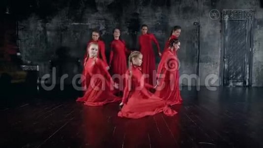 一群年轻的舞女穿着红色长裙在黑暗的大厅里排练，表演视频