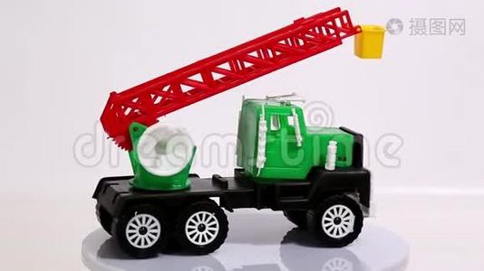 绿色玩具起重机汽车衡模型车在白色背景上旋转。视频