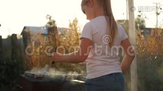 小女孩在绿色草坪的烤架上做烧烤。视频