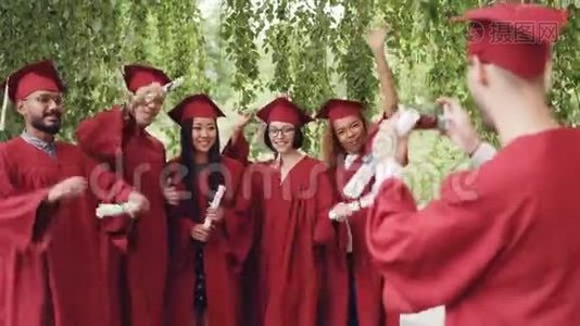 “快乐的家伙”正在用智能手机为那些拿着毕业证书、摆姿势、大笑的同学拍照视频