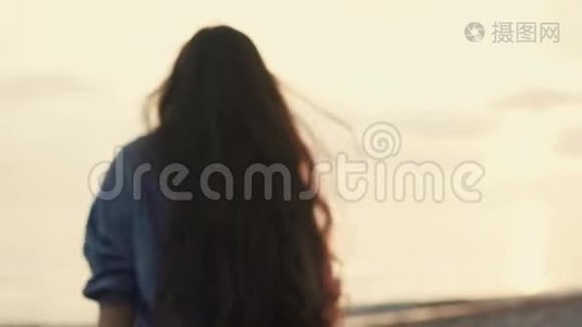 一个年轻的女人跑到海边，晚上海浪拍打着海滩视频