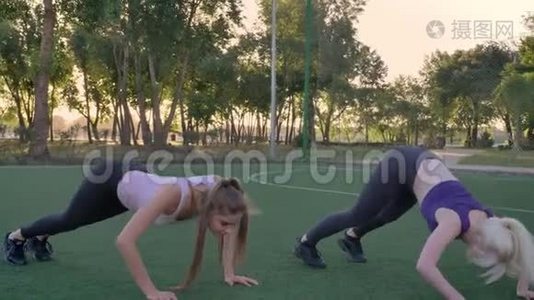 两名年轻女子在公园的足球场上伸展身体，减肥，健身模特运动视频