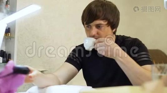 年轻人在修指甲的过程中放松和喝咖啡视频