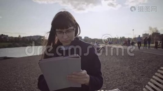 戴眼镜的商务女士在河岸用米黄色的平板电脑。视频