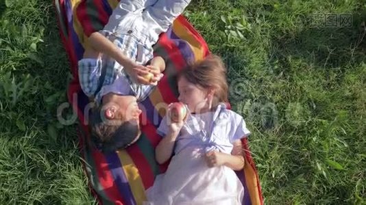 健康的孩子咬苹果，躺在草地上的毯子上视频