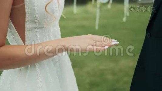 新娘和新郎在绿色自然背景下交换结婚戒指视频