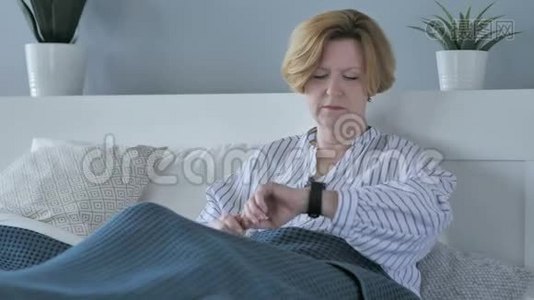 坐在床上等待老年妇女看时间视频