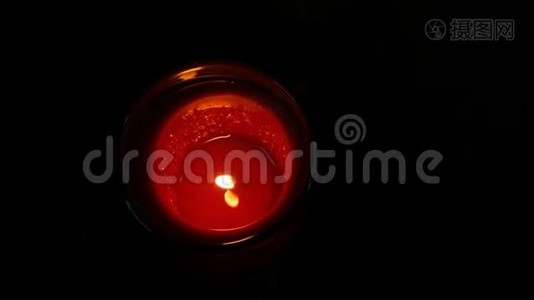 巨大的圆形红色纪念蜡烛在黑暗中燃烧。 黑色背景上的蜡烛火焰视频