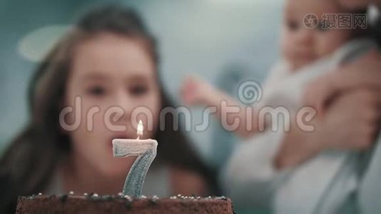 在家庭聚会上，女孩在生日蛋糕上吹蜡烛。 孩子生日快乐视频