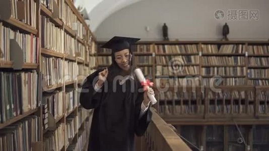 漂亮的学生穿着学术服装，站在图书馆里玩得很开心。视频