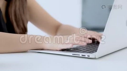特写自由职业妇女微笑着在办公桌办公室的笔记本电脑上工作和打字，配有专业人员视频