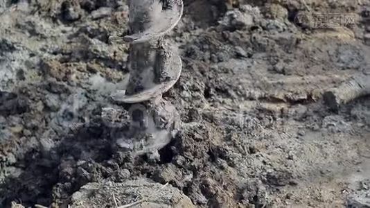 一台钻机的特写在地面上钻了一个洞。 钻转动，抓土..视频