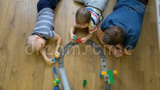 家庭观念。 孩子们和爸爸在木地板上玩火车。 有儿子的父亲。 直接上图视频