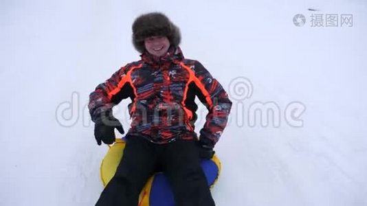 人在雪中滑动，在充气雪管和波浪手。 快乐的人在雪橇上滑过雪。 男人在玩游戏视频