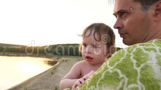小宝宝很伤心，哭着把眼泪滴在爸爸手里，爸爸用毛巾裹在城市海滩上视频