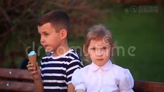 小男孩和小女孩坐在长凳上吃冰淇淋视频