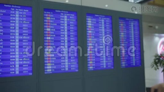 慢动作-快乐的亚洲女人看着信息板，用行李在候机大厅检查她的航班。视频