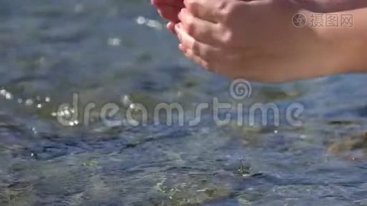 女子双手抓举清澈见底的淡水在户外的山河中，滴入水面视频