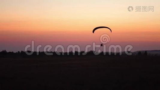 滑翔伞上的飞行员在日落后用橙色在天空中飞行。 背景视频