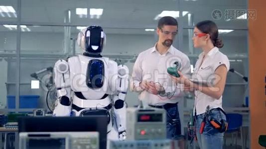 男性和女性工程师正在阅读带有特殊设备的类似人类的机器人视频