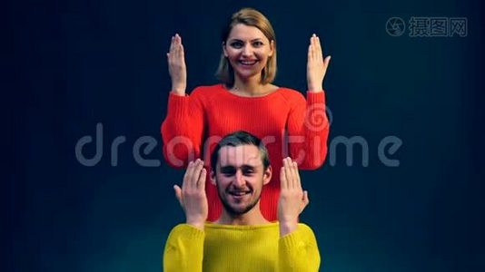 一个穿红色衣服的女孩和一个穿黄色毛衣的男孩，拥抱他们的手在黑色背景上表现出不同的情绪。 情绪视频