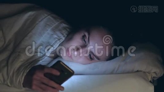 女人使用手机，晚上躺在床上视频
