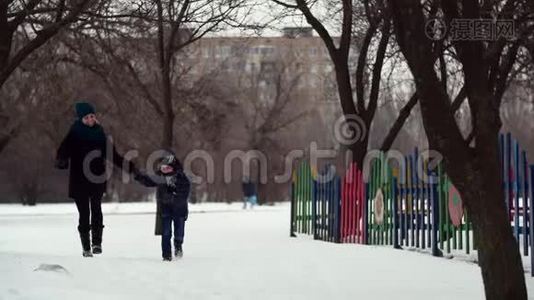 HD母亲和儿子一起在冬季公园里奔跑，手牵手视频