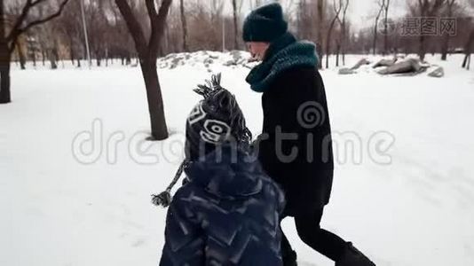 高清母子正快乐地在大雪覆盖的冬季公园里奔跑视频
