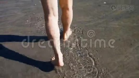 黄种人老人用黑沙在水中的岸边散步视频