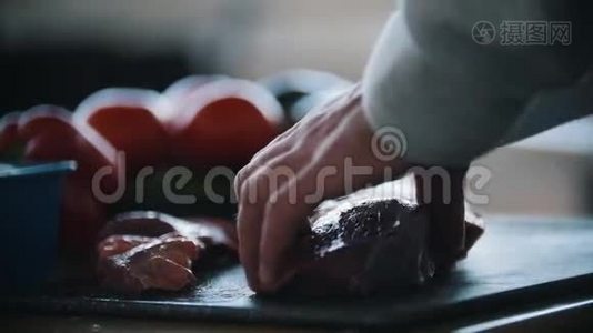 手男子切肉牛排用刀特写. 背景上美味可口的新鲜蔬菜番茄视频