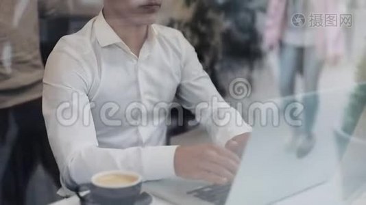 一个疲惫的年轻商人坐在咖啡馆的一张桌子旁用笔记本电脑工作。自由职业者，沟通，IT，疲惫视频
