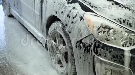 洗车。 洗车机清洗汽车。 车上覆盖着白色的冲洗泡沫.. 特写镜头。视频