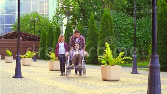 十几岁的女孩和一个男人在公园里抱着一个坐轮椅的残疾妇女。 慢节奏视频