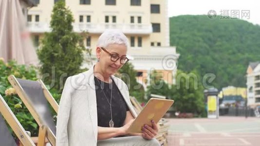 微笑优雅的女人在街上休息，有美丽的自然和建筑。视频