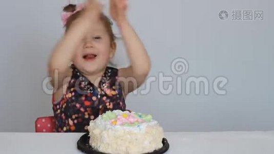 生日快乐。 一个可爱的女孩微笑，高兴，鼓掌，吃蛋糕，舔她的手指。视频