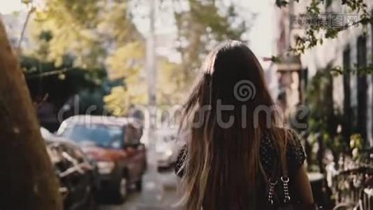 后景快乐的白种人女孩带着飞扬的头发走在阳光明媚的城市街道上，生活随意的生活方式慢动作。视频