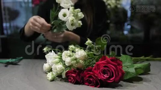 专业的花艺师把白色和红色的玫瑰花剪在桌子上，女人的手`特写。视频