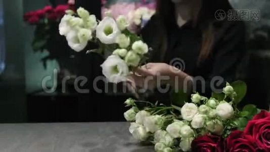 专业的花艺师把白色和红色的玫瑰花剪在桌子上，女人的手`特写。视频