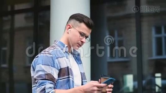城市街道上的一次性纸杯上有智能手机喝咖啡的人的肖像。 英俊的年轻人视频