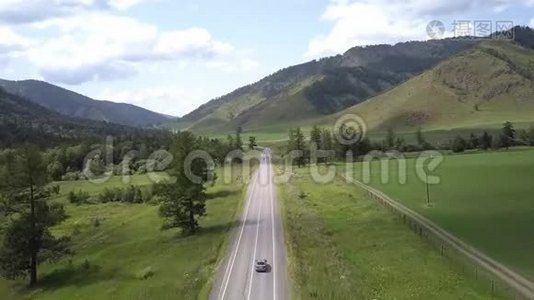 空中飞行在田野和山脉之间的道路上。 夏日阳光明媚。 在路上路过汽车。 阿尔泰共和国视频