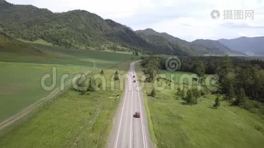 空中飞行在田野和山脉之间的道路上。 夏日阳光明媚。 在路上路过汽车。 阿尔泰共和国视频