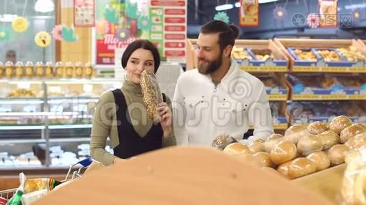 一对年轻夫妇在超市的肖像，同时选择新鲜面包。视频