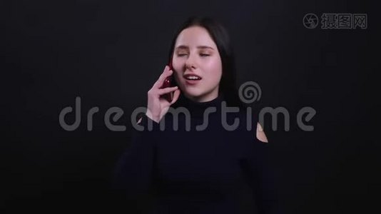 一位年轻漂亮的黑发女性的特写镜头，她打着电话，愉快地交谈着，背景与外界隔绝视频