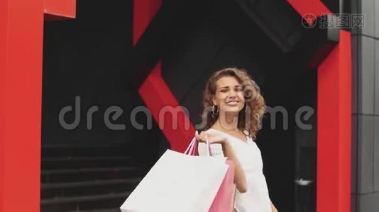 美丽的女人拿着购物袋微笑着。 购物中心背景视频