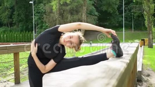小女孩在公园的木桥上做伸展运动。 训练前热身。 慢动作。视频